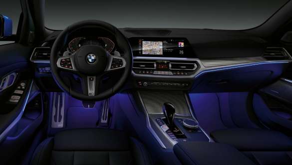 BMW 3 Series Sedan, Ambient light. Front view of the driver's cockpit of the BMW 3 Series Sedan with by Ambient light blue illuminated legroom.