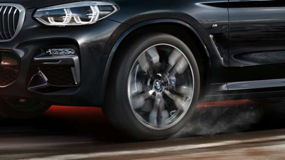 BMW X3 M40i and BMW X3 M40d SUV G01, side view. BMW X3 M40i and BMW X3 M40d SUV G01 in Black Sapphire metallic, driving, exterior, side view with rotating light alloy wheel.
