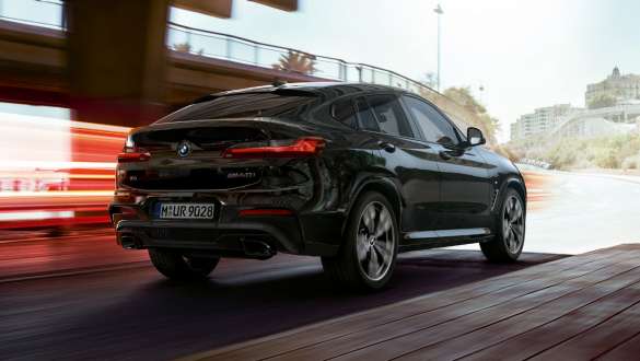 BMW X4 M40i and BMW X4 M40d SUV G02, three-quarter rear view. BMW X4 M40i and BMW X4 M40d SUV G02 in Black Sapphire metallic, driving, exterior, three-quarter rear view with light strips.