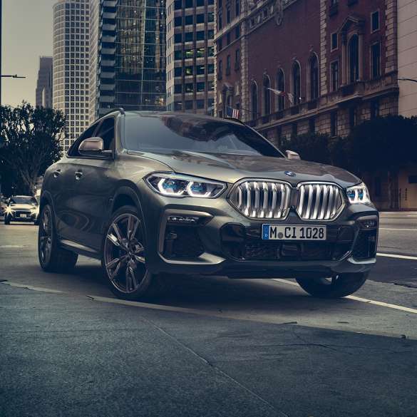 BMW X6 SUV G06 Adaptive M suspension Professional BMW X6 SUV G06 in three-quarter front perspective in front of an urban setting.