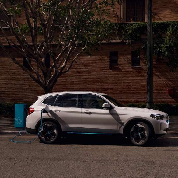 High-Power Charging BMW iX3 SUV G08 side view at public charging station High-Power Charging BMW iX3 SUV G08 2020 Mineral White metallic side view at public charging station