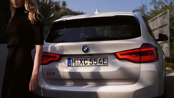 Rear with BMW i specific diffuser BMW iX3 SUV G08 rear view with woman Rear with BMW i specific diffuser BMW iX3 SUV G08 2020 Mineral White metallic rear view with woman