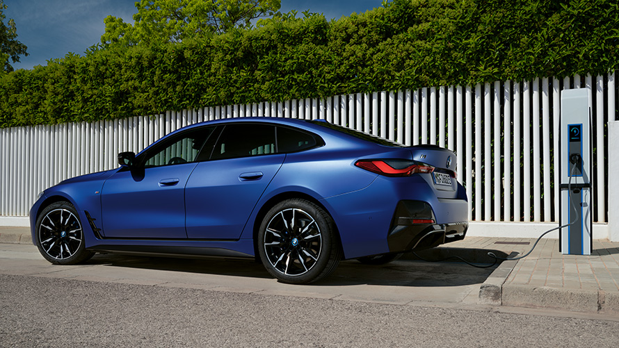 BMW i4 M50 G26 2021 BMW Individual Frozen Portimao Blue metallic side view at a public fast-charging station