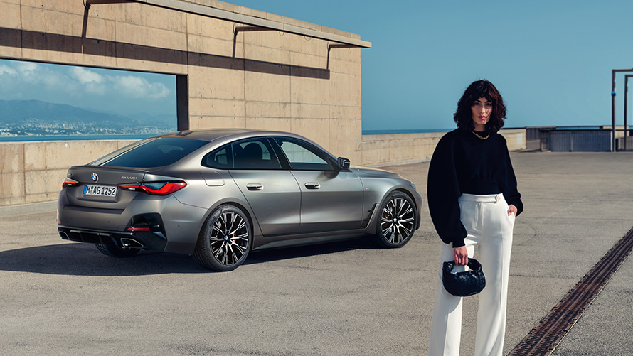 BMW M440i xDrive Gran Coupé G26 2021 three-quarter rear view with model BMW M440i xDrive Gran Coupé G26 2021 three-quarter rear view with model