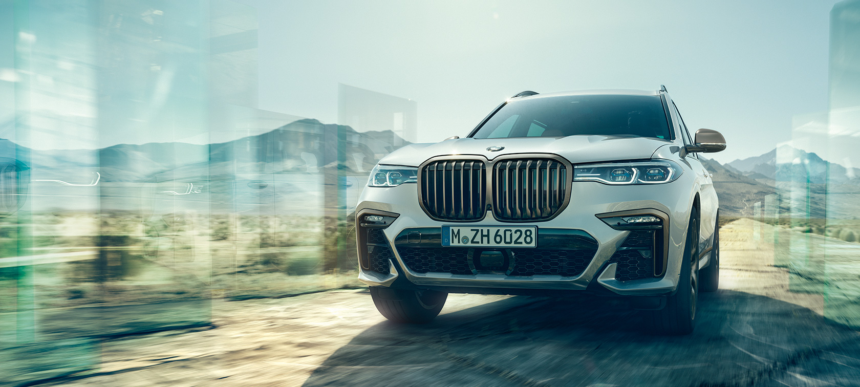 BMW X7 M50d M Automobile G07 2019 Mineral White driving on highway three-quarter rear view