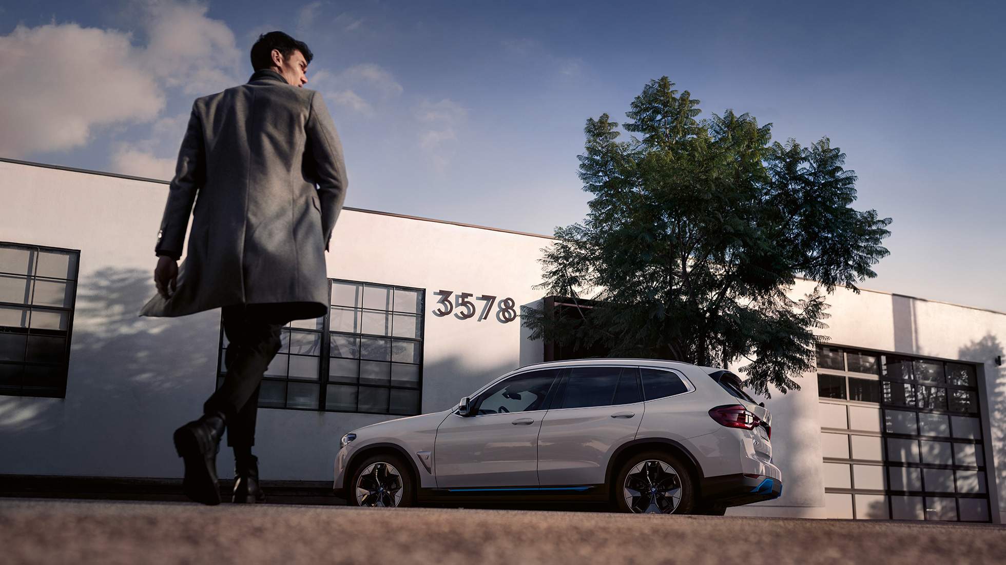 BMW iX3 G08 side view in front of building with man BMW iX3 G08 2020 Mineral White metallic side view in front of building with man