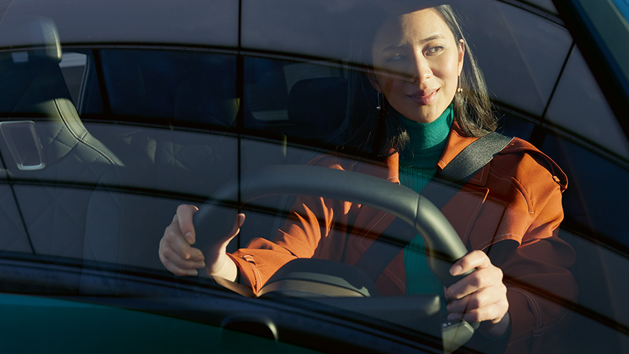 Woman at the steering wheel of a BMW Woman in orange jacket at the steering wheel of a BMW