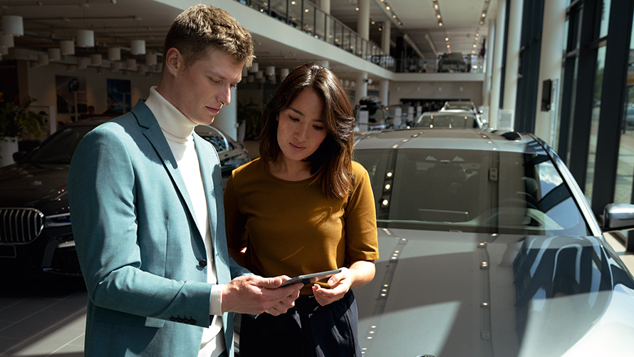 BMW customer advisor advises customer via tablet inside the BMW showroom 